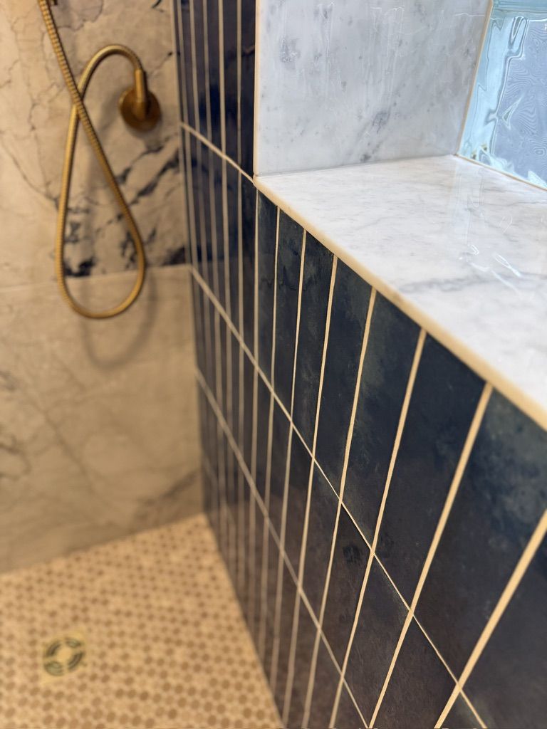 Close-up where blue vertical tile meets the marble niche shelf