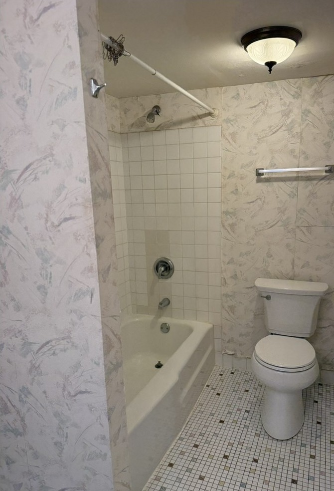 Before renovation: original tub and shower combo with beige tile
