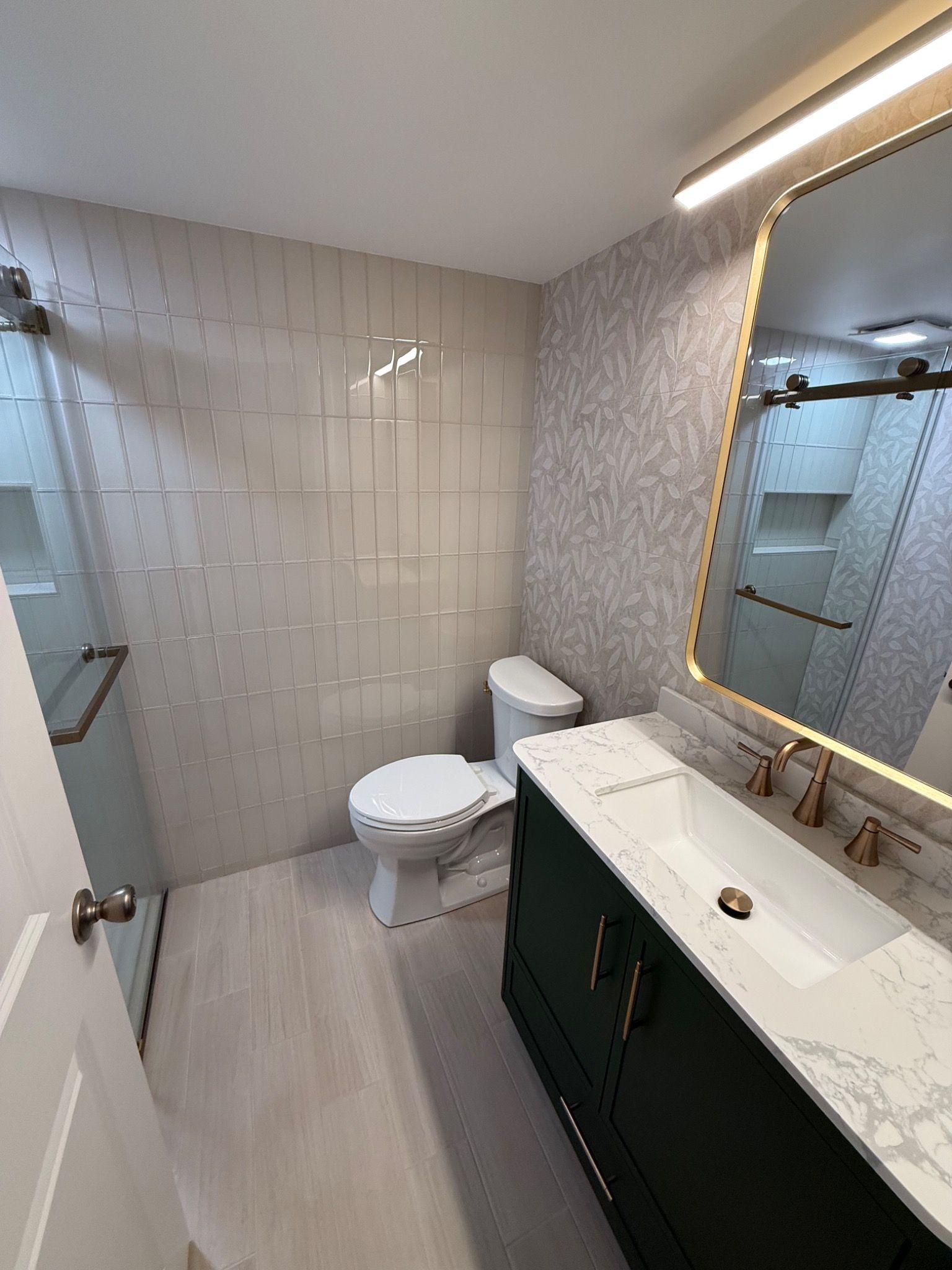 Bathroom remodel with green vanity and glass shower from the doorway