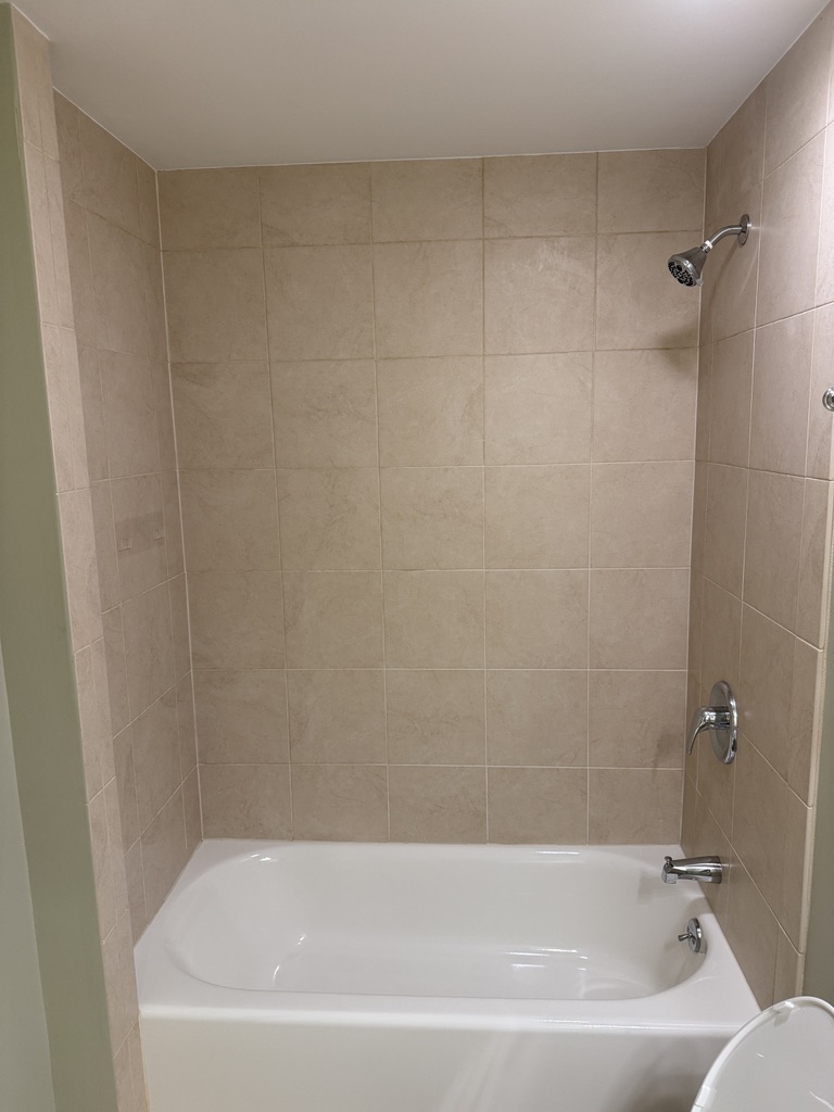 Before renovation: original tan tile tub and shower surround