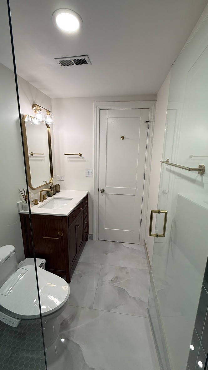Finished vanity, closet door, and shower glass viewed from the hallway