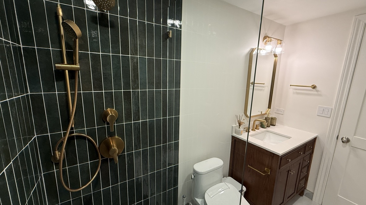 Hunter green tile bathroom remodel with walk-in glass shower and gold fixtures