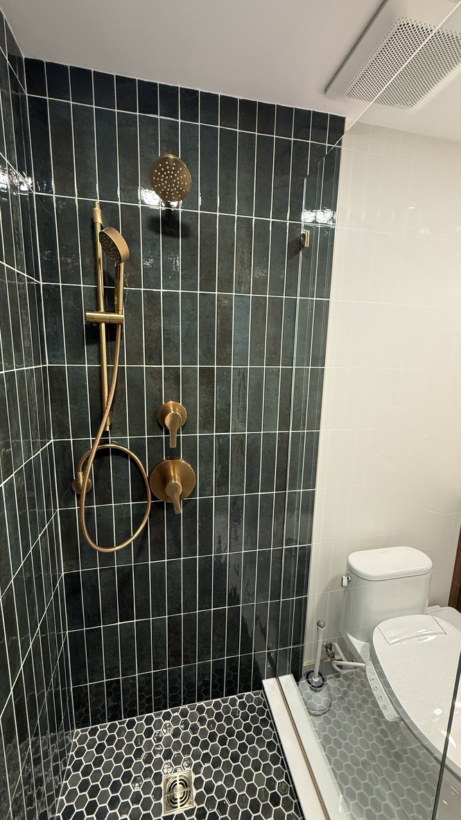 Close-up of the gold shower fixtures and hunter green vertical tile