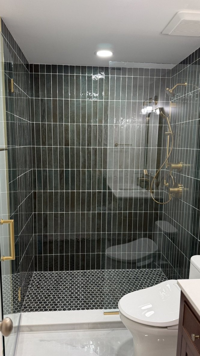 Full view into the finished hunter green tile shower with gold fixtures