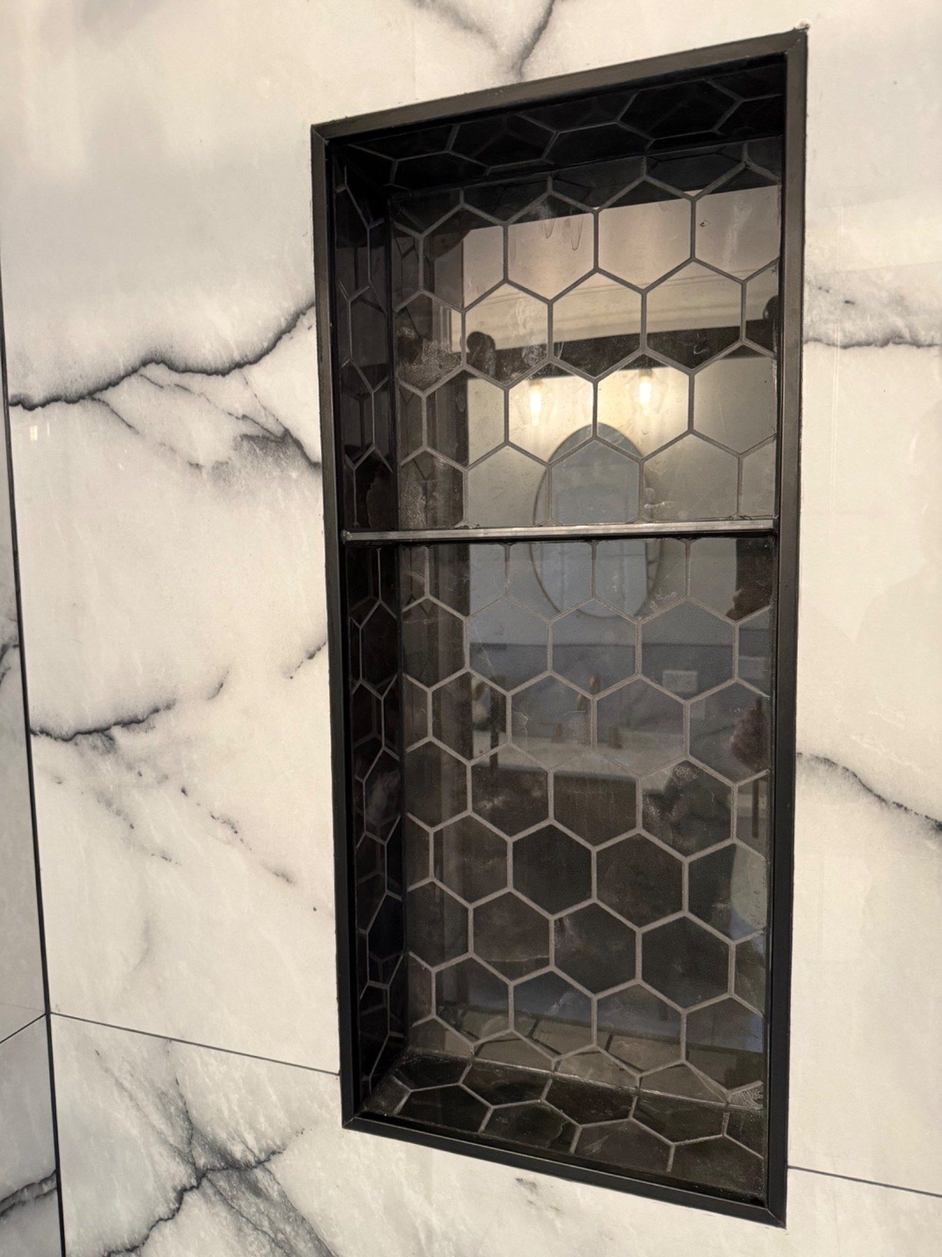 Black niche detail set into large-format marble-look tile
