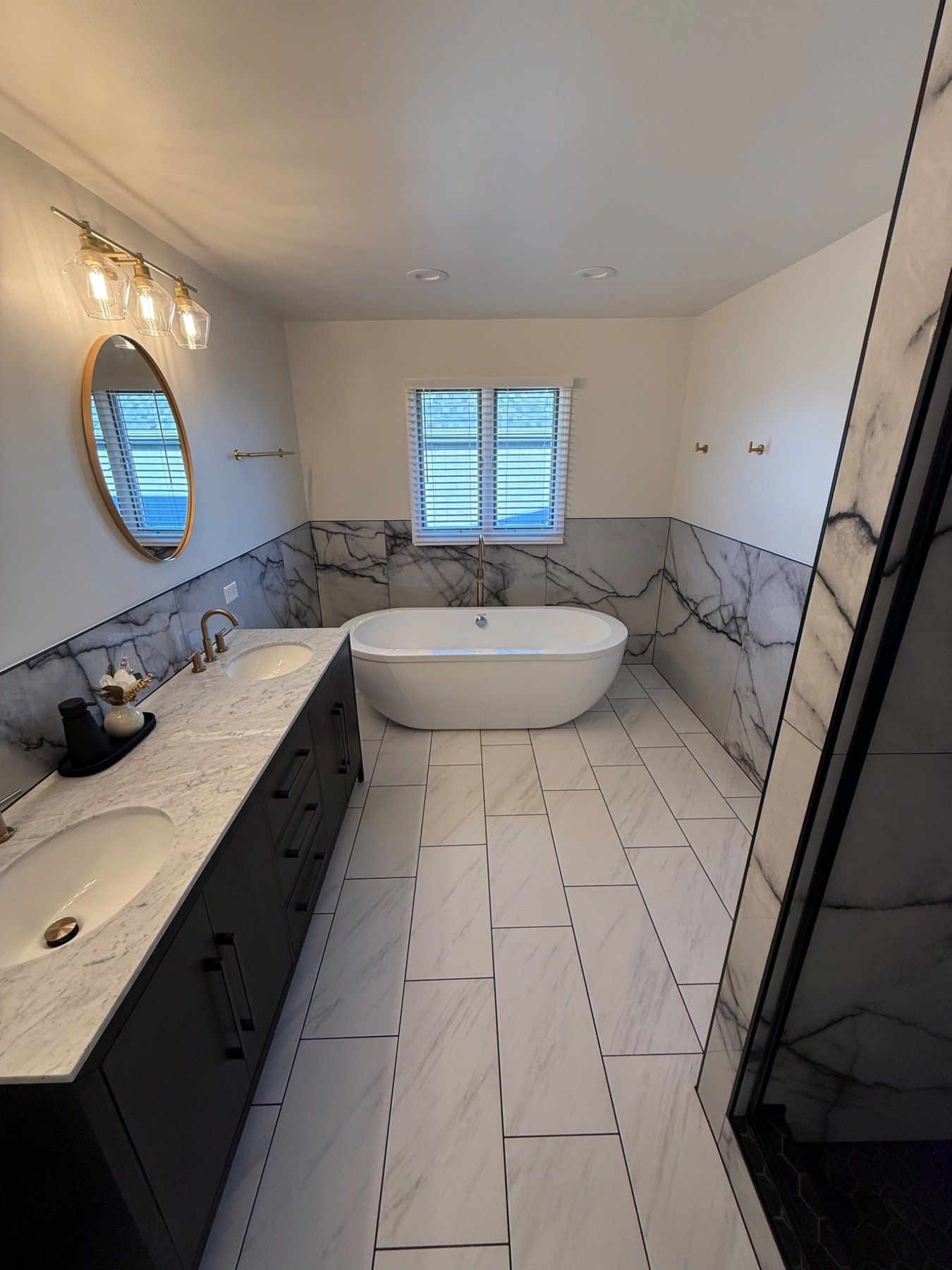 Large primary bathroom remodel with freestanding tub, double vanity, and marble-look walls