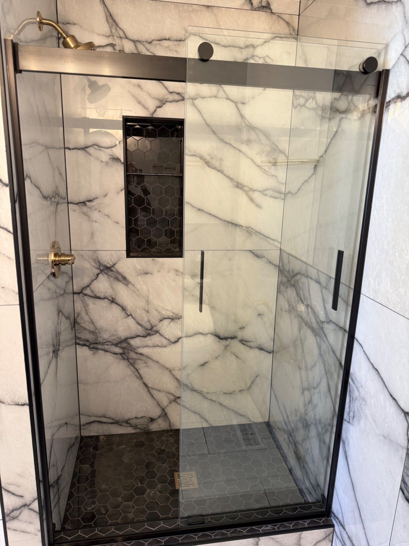 Glass shower with marble-look walls and black trim