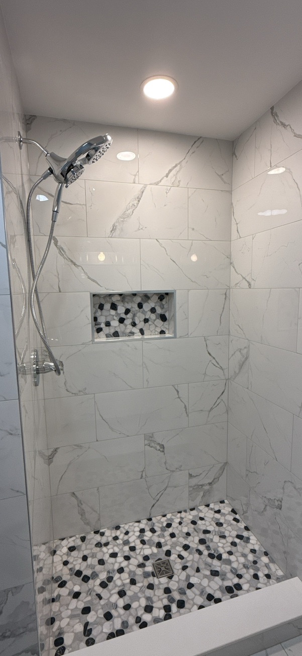Pebble floor bathroom remodel with white marble tile shower and mosaic floor