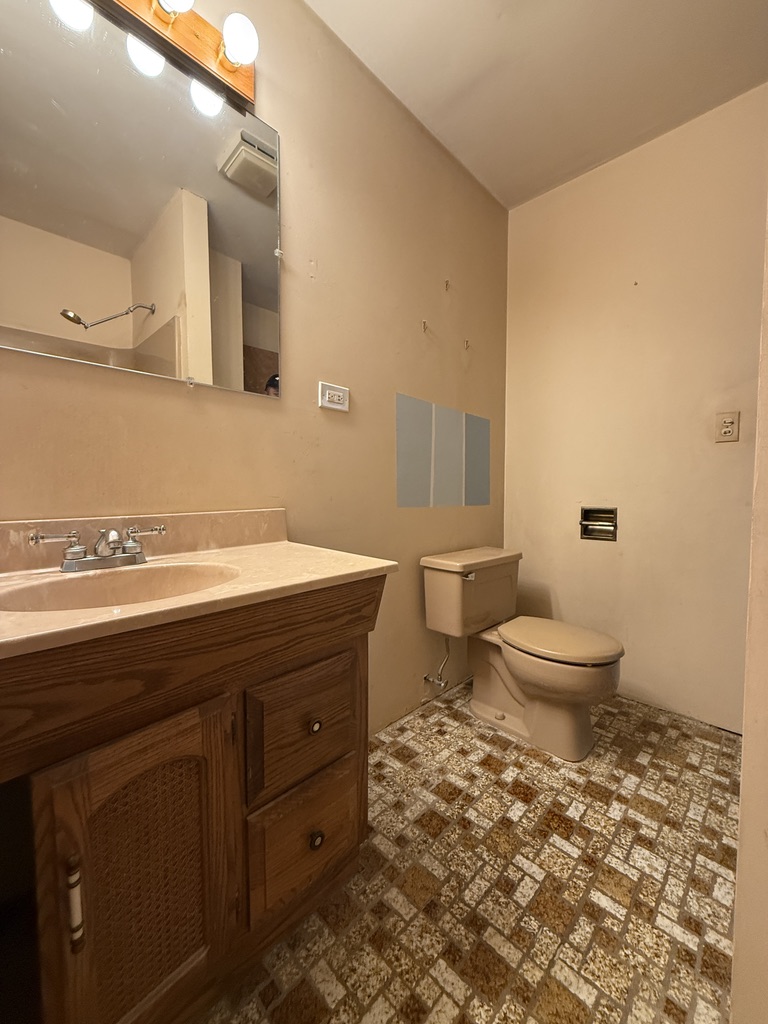Before renovation: original toilet and vanity with dated tile floor