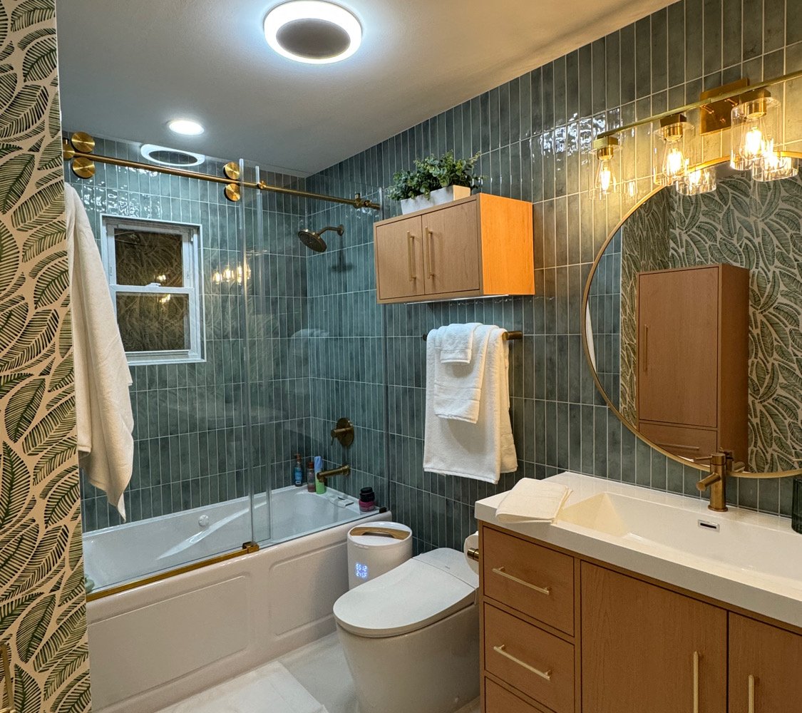 After renovation: green tile with botanical wallpaper and round mirror