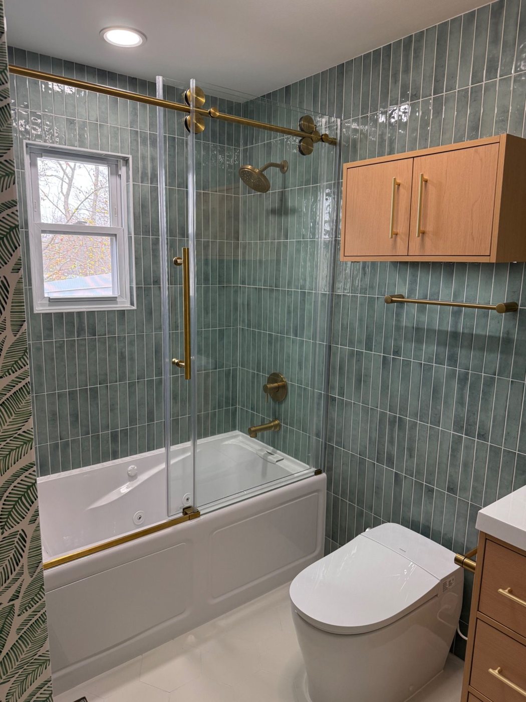 Wide angle of bathroom remodel with tub, vanity, and green wall tile