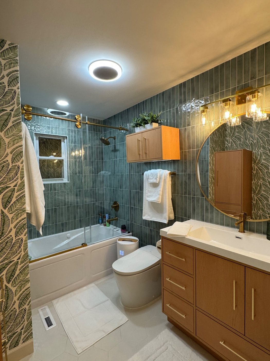 Finished tropical bathroom remodel with tub, vanity, and wallpaper from the doorway