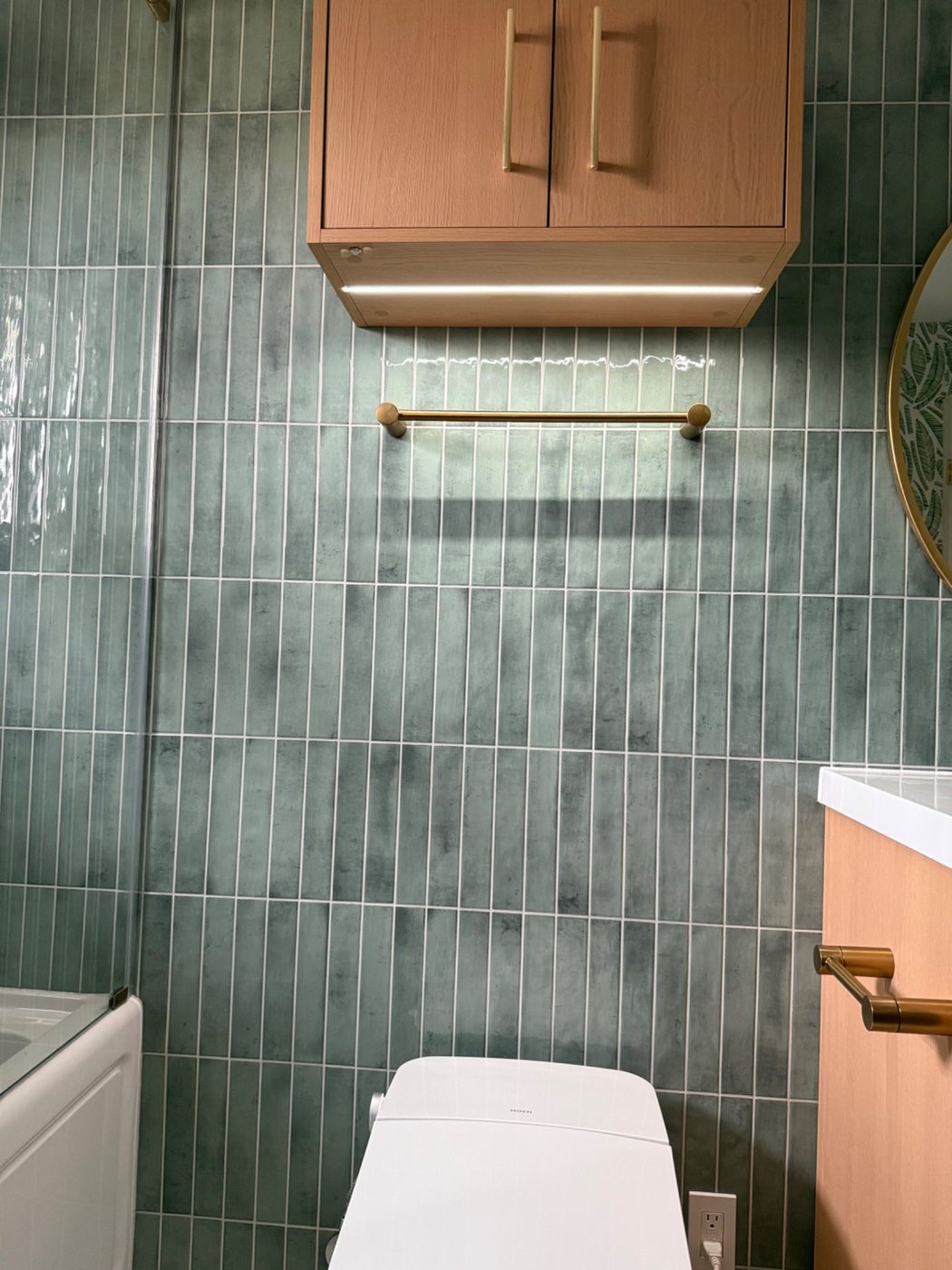 Towel bar and wall cabinet detail on glossy green tile