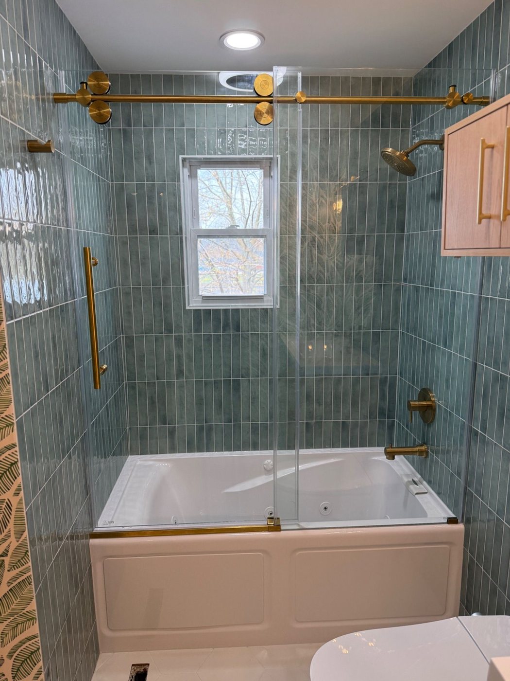 Front view of tub with sliding glass and green wall tile