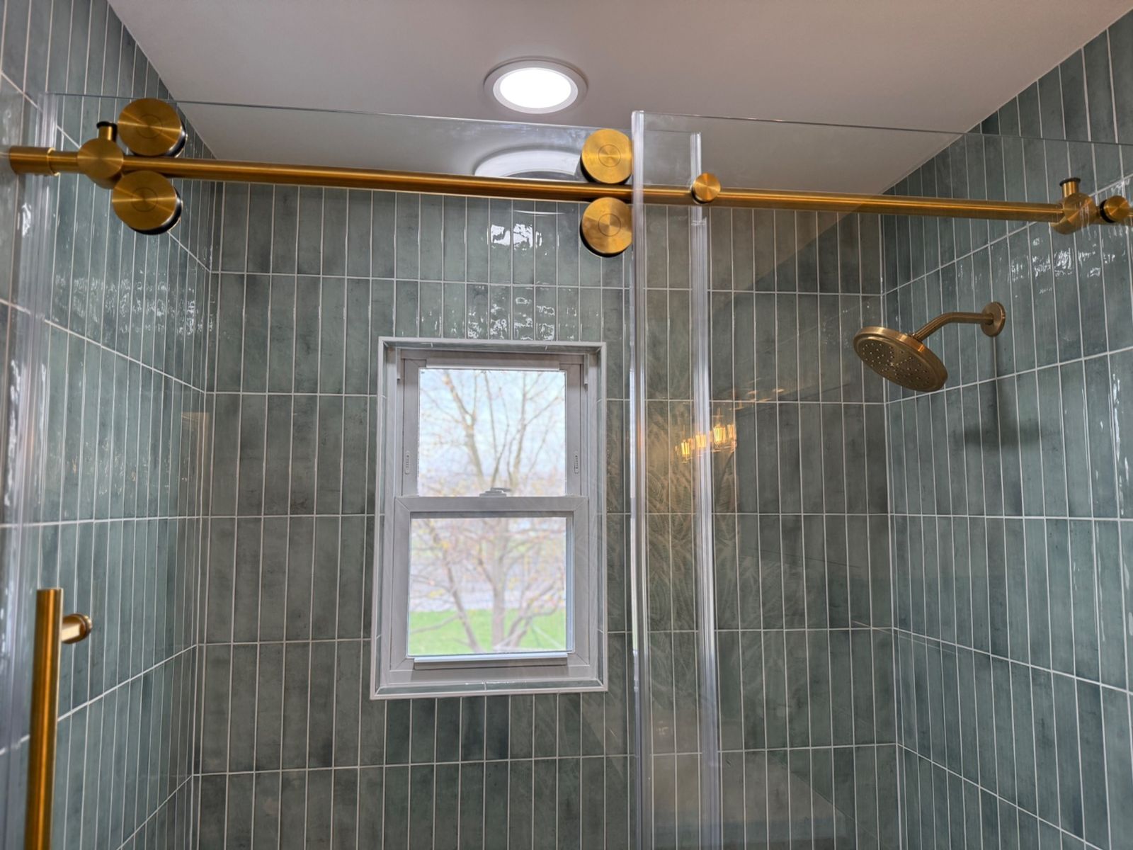 Window view framed by glossy green shower tile and glass