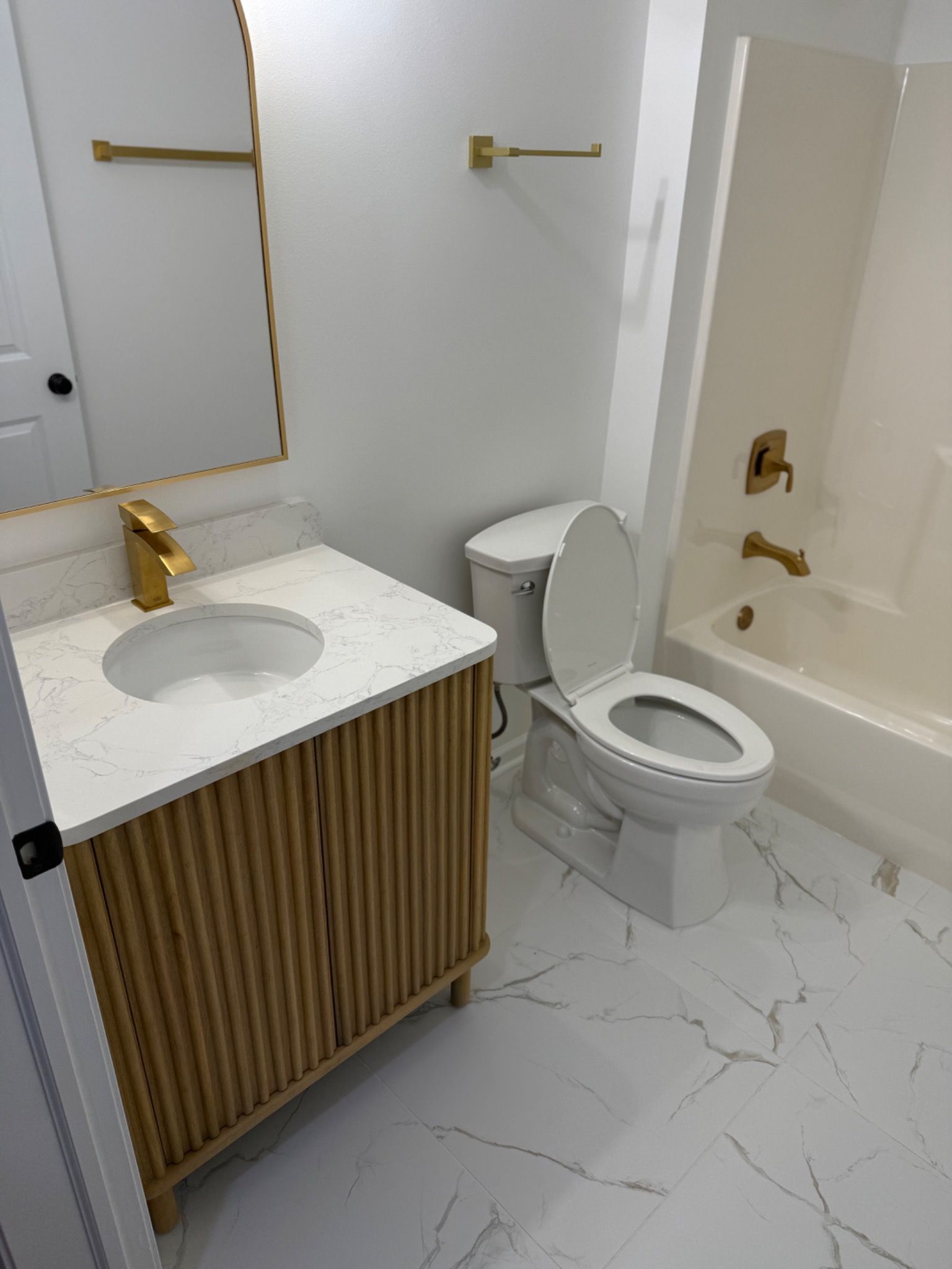 Closer view of fluted vanity, mirror, and warm brass fixtures