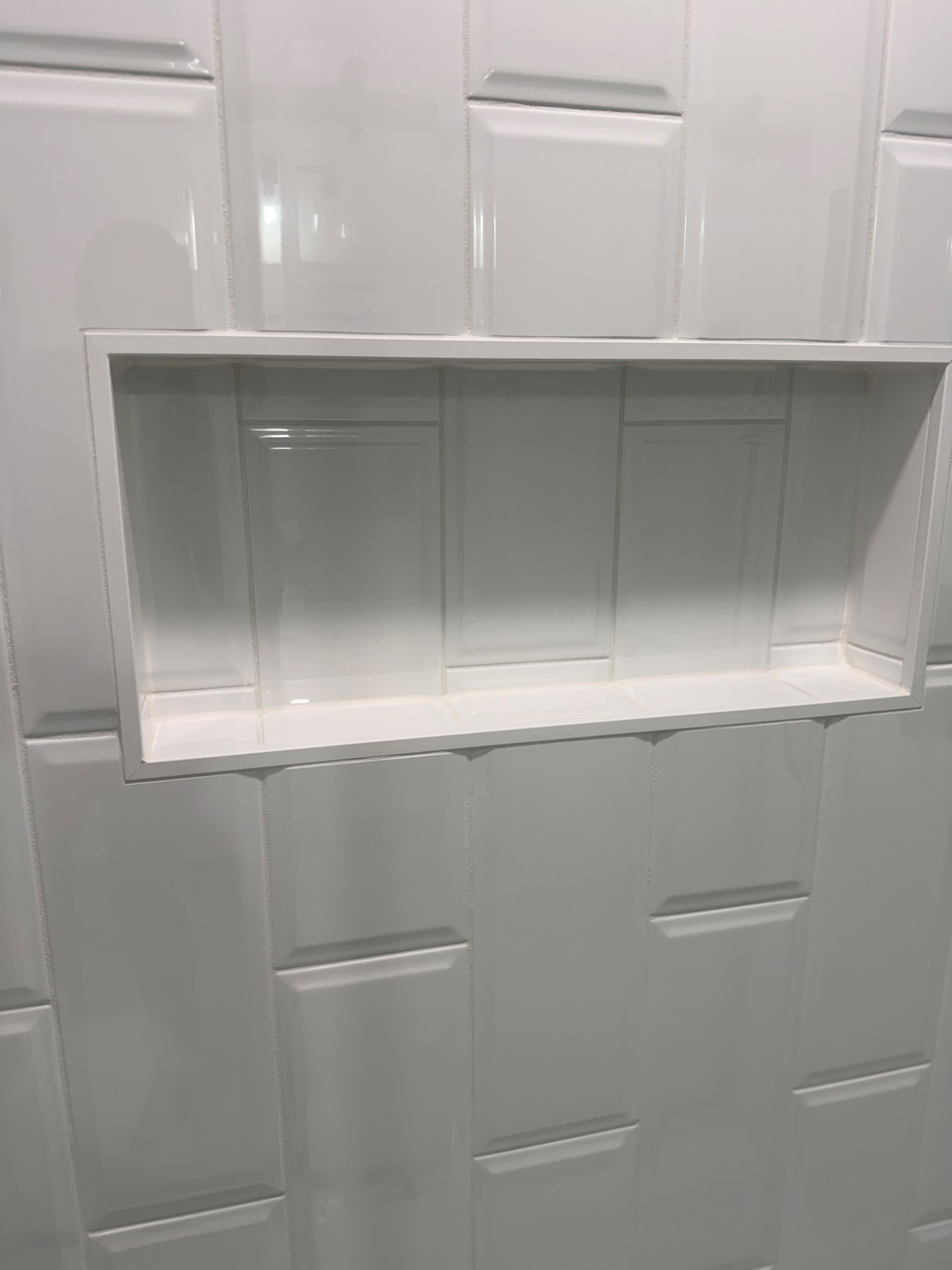 Shower niche framed in white tile