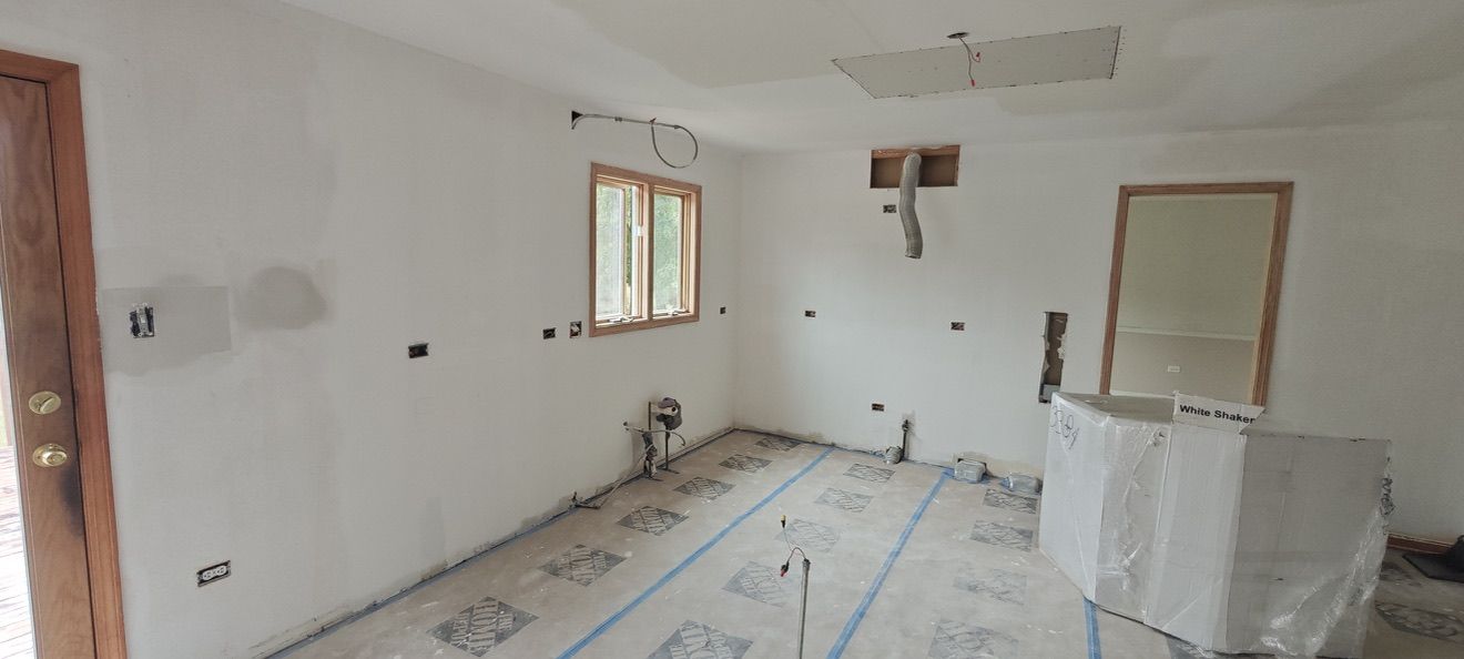 Fresh drywall with a wrapped White Shaker cabinet box ready to install