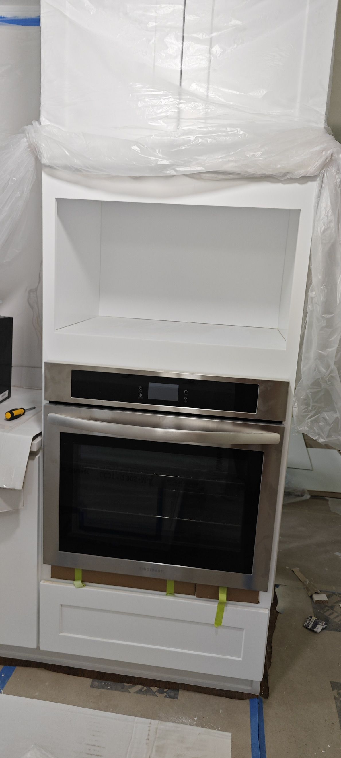 Built-in wall oven being installed in the cabinet tower