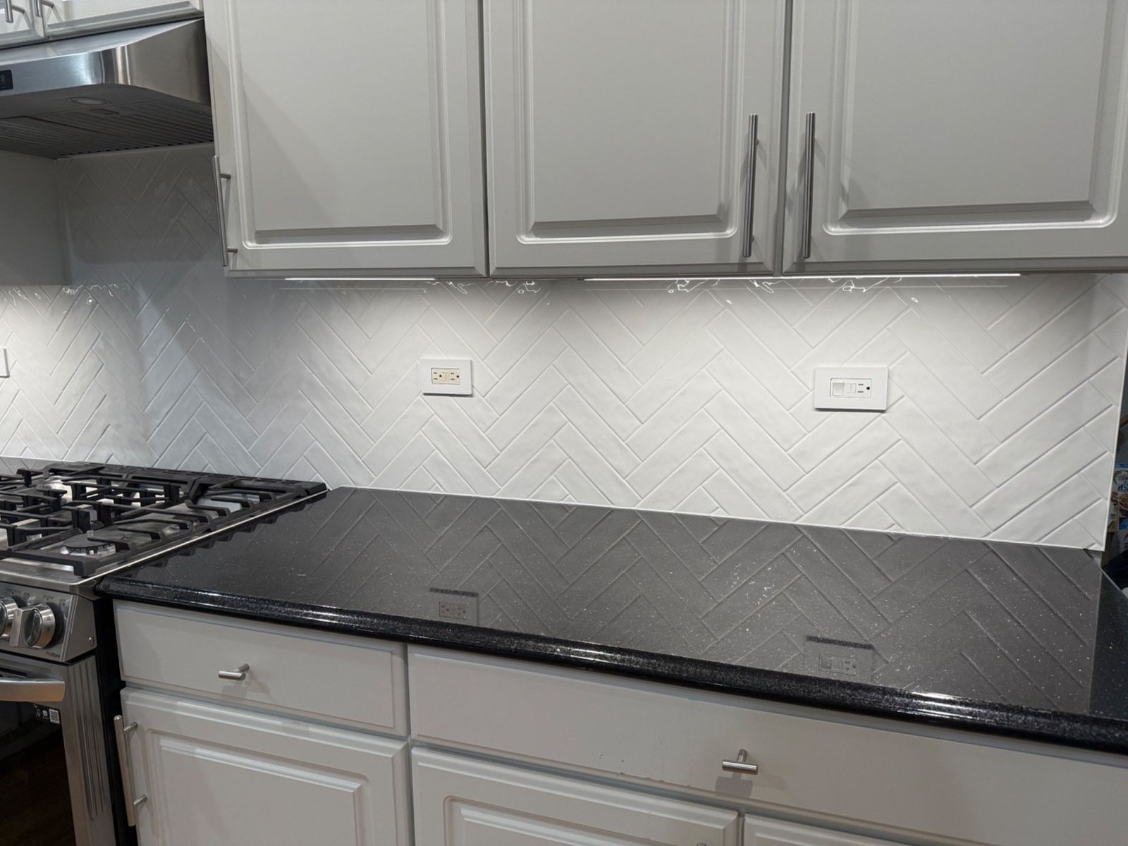 Kitchen backsplash tile installed above black countertop