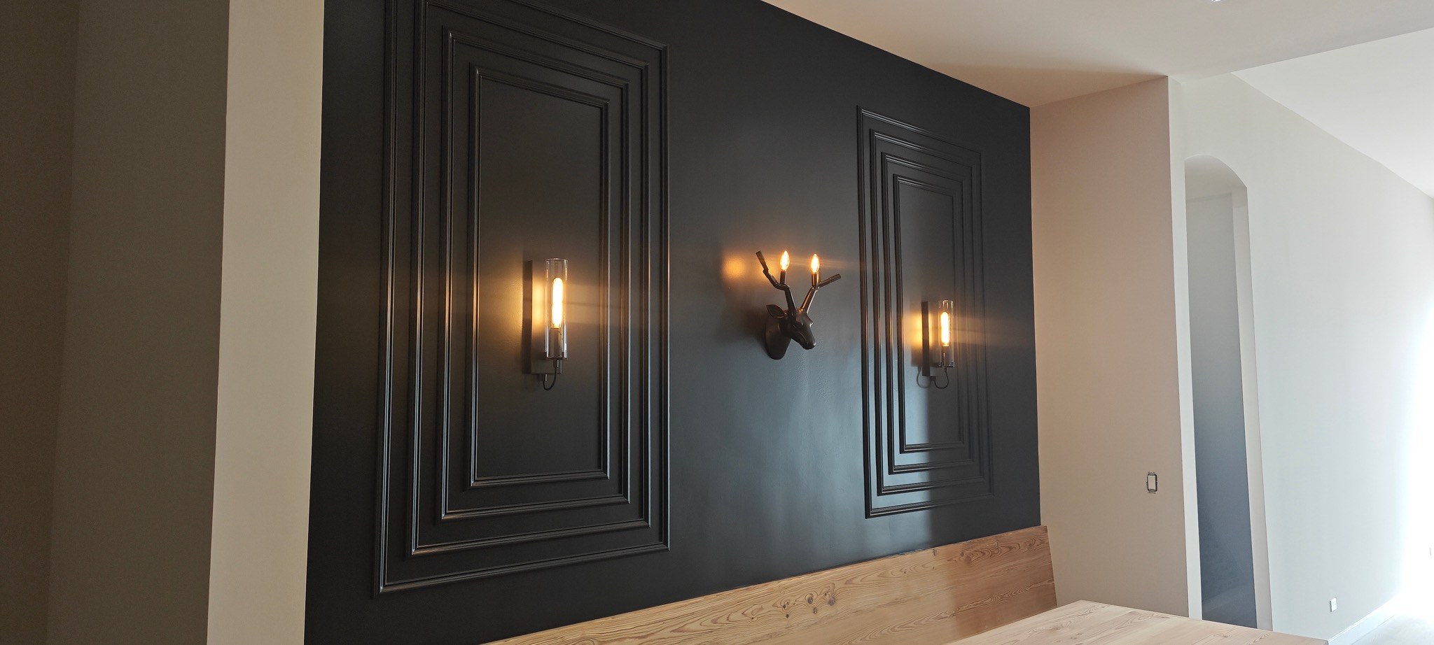 Wide view of black painted decorative feature wall with sconces